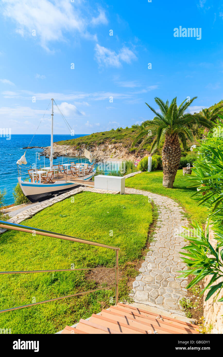 Path to traditional sailing boat in green area of Proteas bay on coast of Samos island, Greece Stock Photo