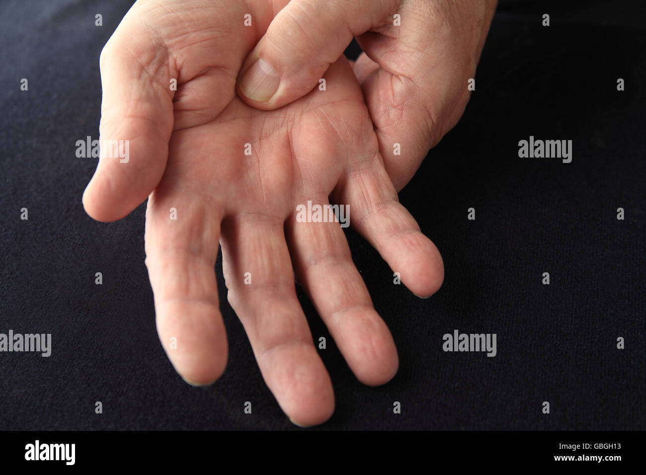 Closeup of older man with painful palm on black background Stock Photo