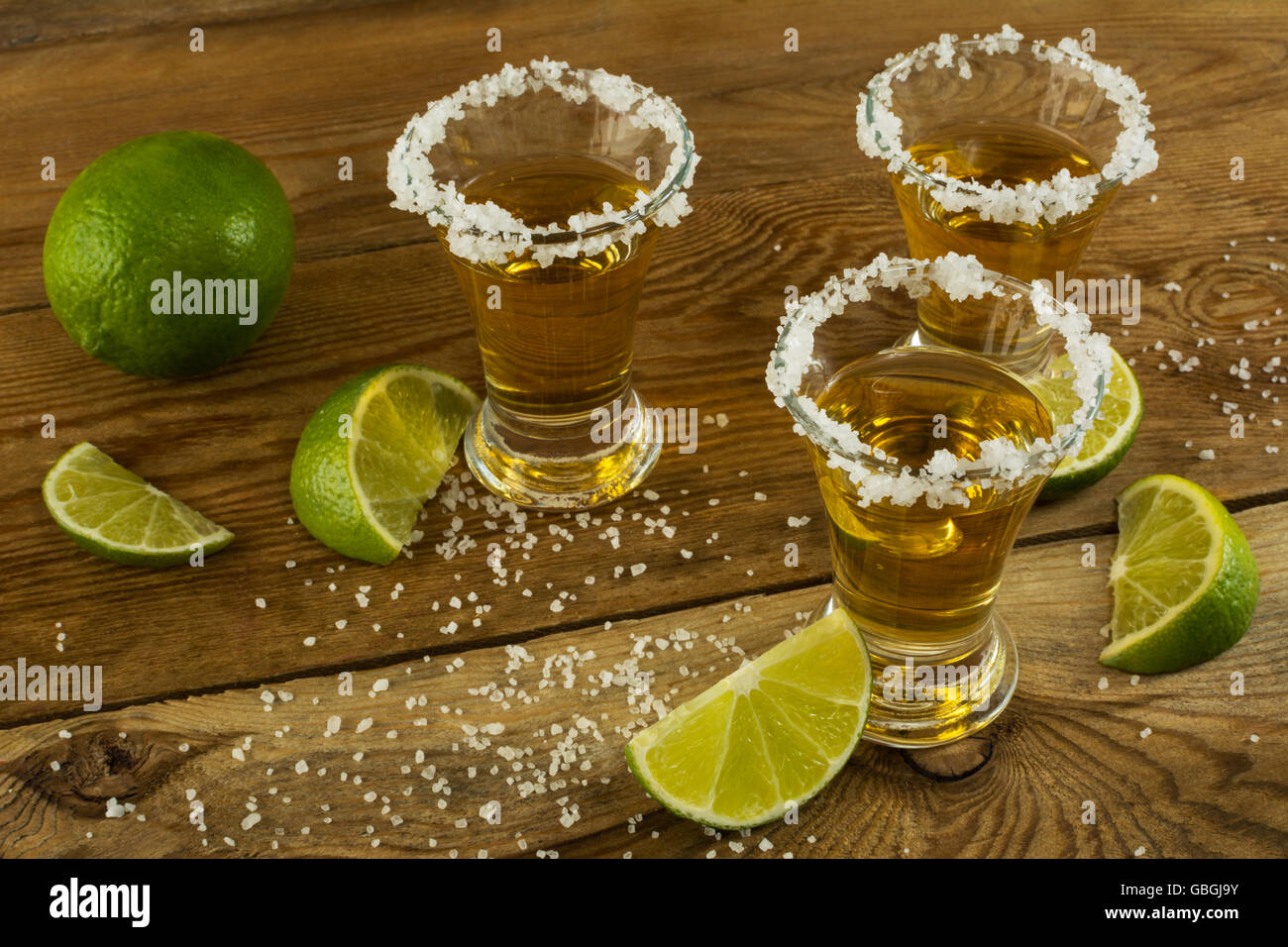 Gold tequila shots on the rustic wooden table. Tequila. Gold Mexican