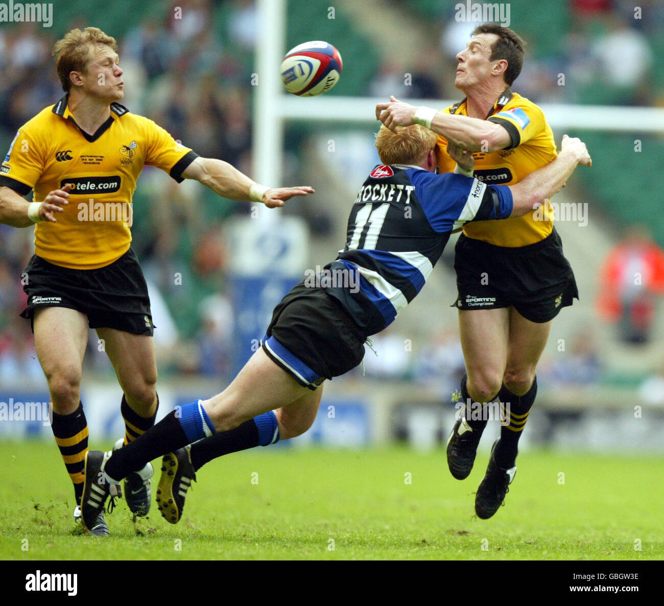 London Wasps' Rob Howley (r) offloads the ball to teammate Josh Lewsey (l) as he is tackled by Bath's Alex Crockett (c) Stock Photo