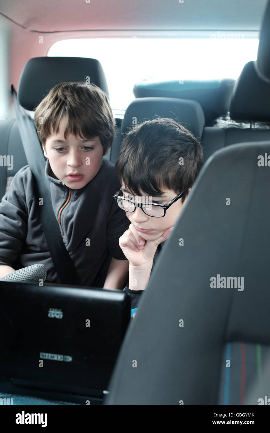 children watching DVD player in rear seat of car Stock Photo
