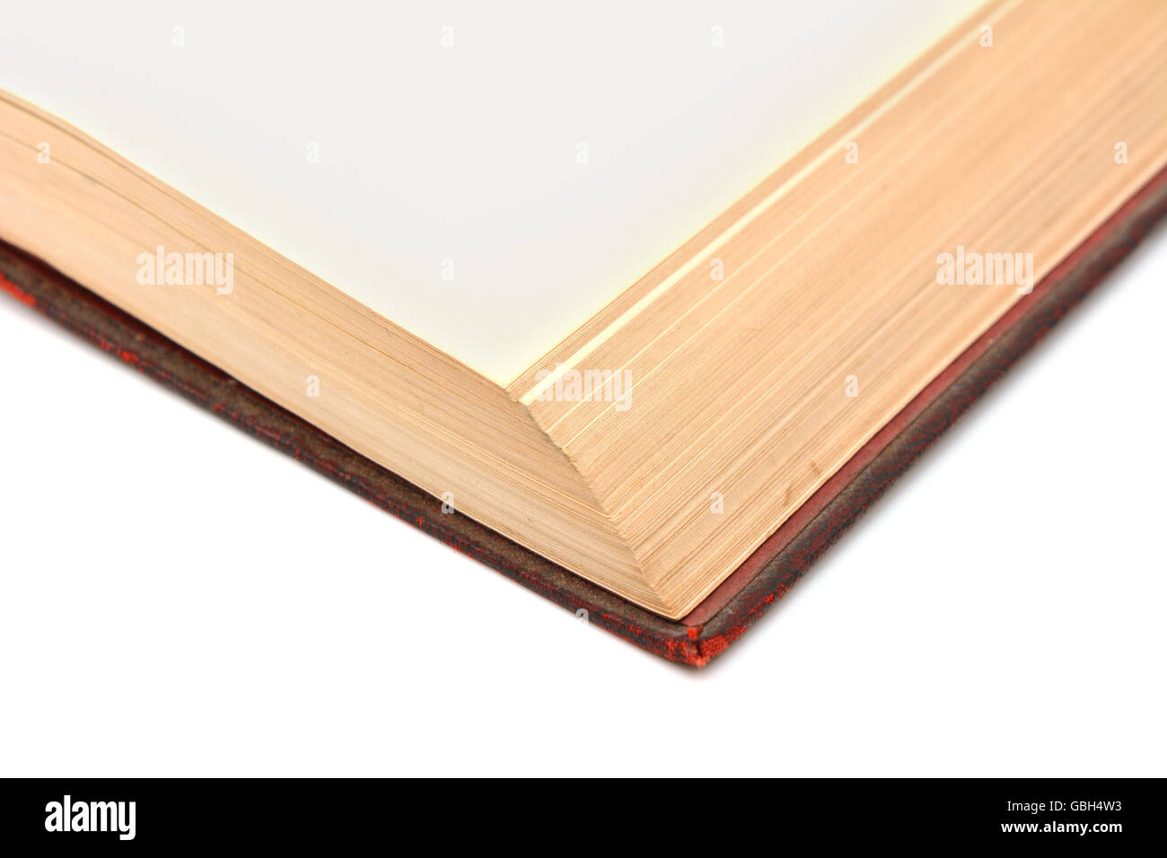Corner detail of a blank page in a shabby, bound hardback book on a white background Stock Photo