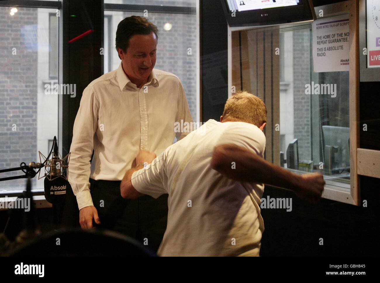 Conservative Leader David Cameron (left) with James Bond stuntman Derek Lea, during his guest appearance on the Breakfast Show with Christian O'Connell, at Absolute Radio in central London. Stock Photo