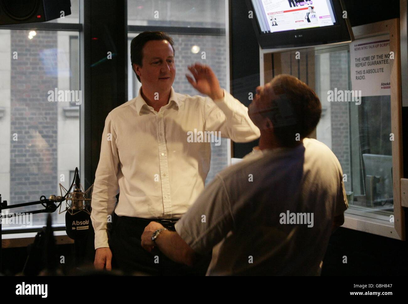 Conservative Leader David Cameron (left) with James Bond stuntman Derek Lea, during his guest appearance on the Breakfast Show with Christian O'Connell, at Absolute Radio in central London. Stock Photo