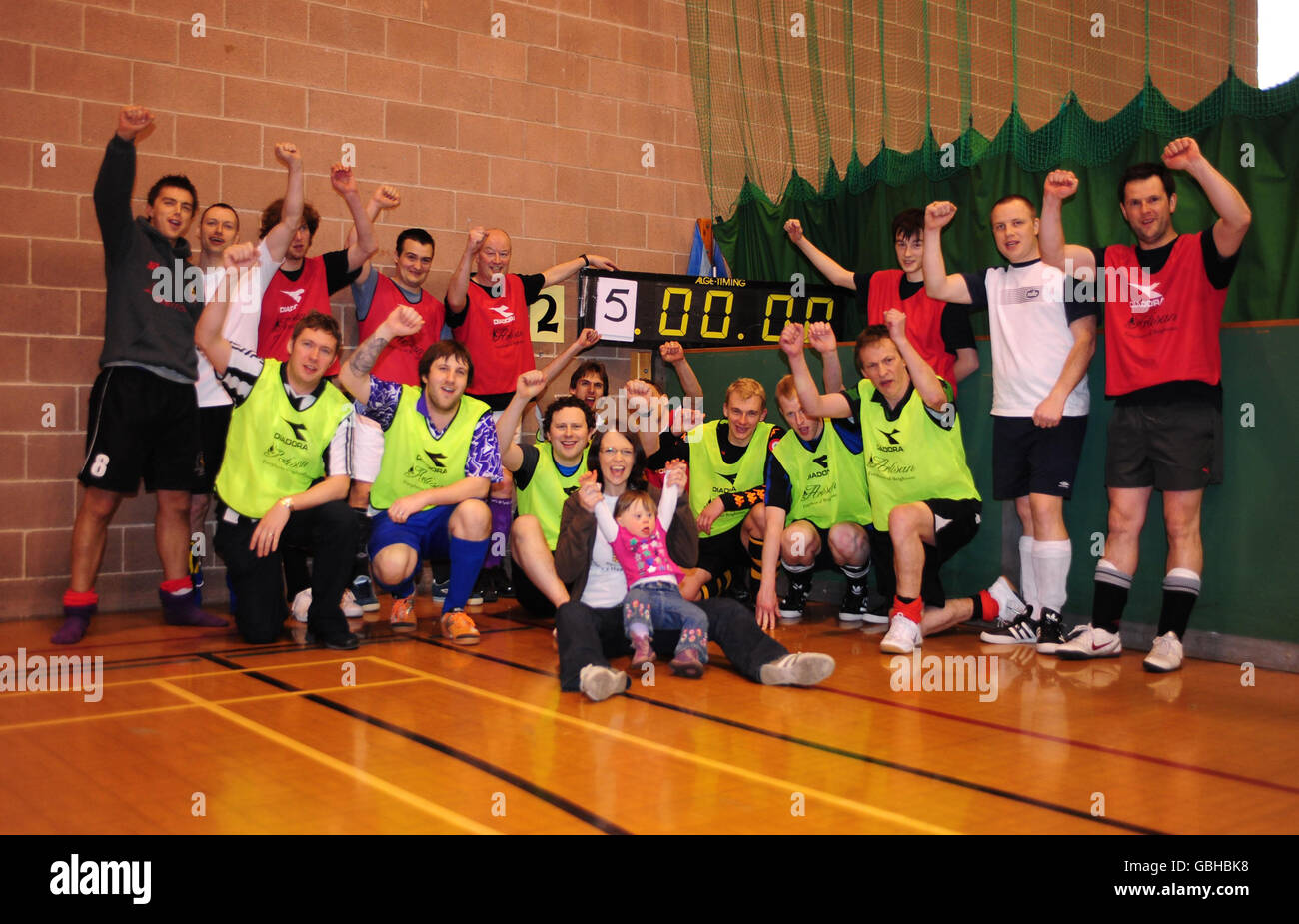 Andrea Arnold sits with her Daugther Zoe in front of the Lionhearts including Jon Arnold (Behind Andrea to the left) and Bravehearts after they successfully set a new Five-A-Side football World record at 25 hours exactly to raise money for the Children's Heart Surgery Fund at Leeds General Infirmary where Zoe received treatment. The record was set at the Leeds University Sport Hall, Leeds. Stock Photo
