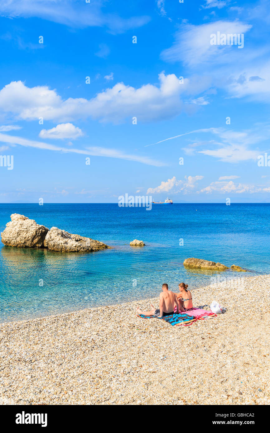 SAMOS ISLAND, GREECE - SEP 24, 2015: Couple of young people relaxing on beautiful Kokkari beach, Samos island, Greece Stock Photo