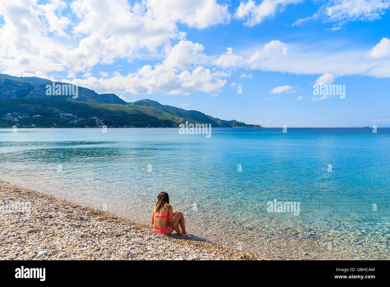 Young woman sitting on beautiful Kokkari beach, Samos island, Greece Stock Photo
