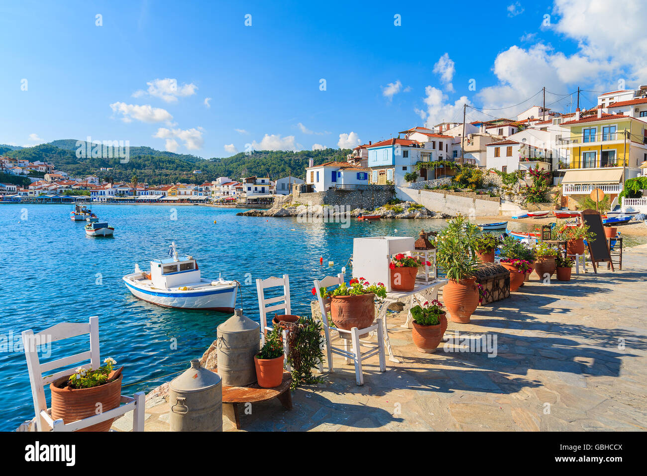 Flower pots on and view of fishing boats anchoring in Kokkari bay, Samos island, Greece Stock Photo