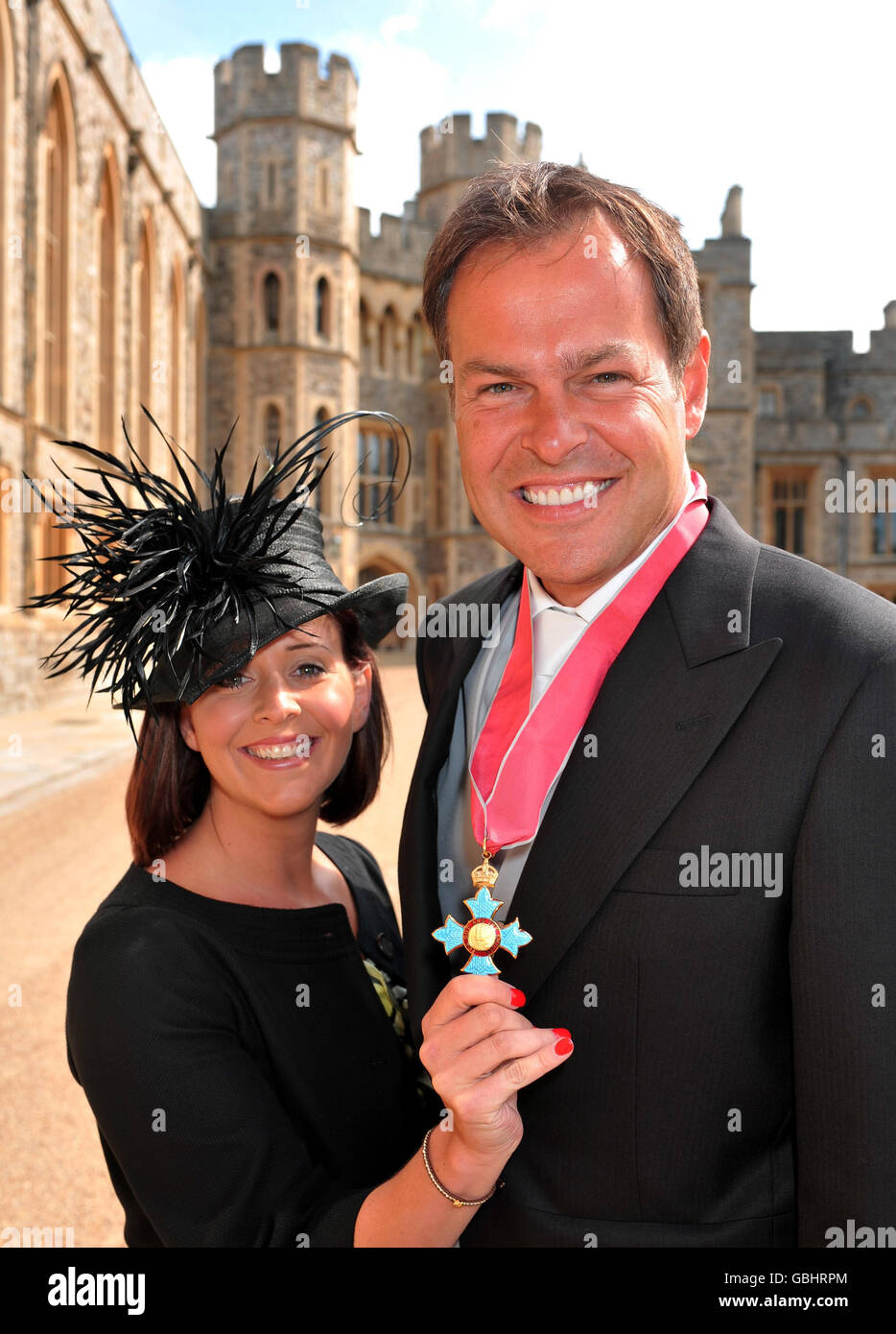 Peter Jones of the Dragon's Den TV show with his wife Tara, as she holds his CBE, after the Queen presented it to him at Windsor Castle, during the Investiture ceremony. Stock Photo