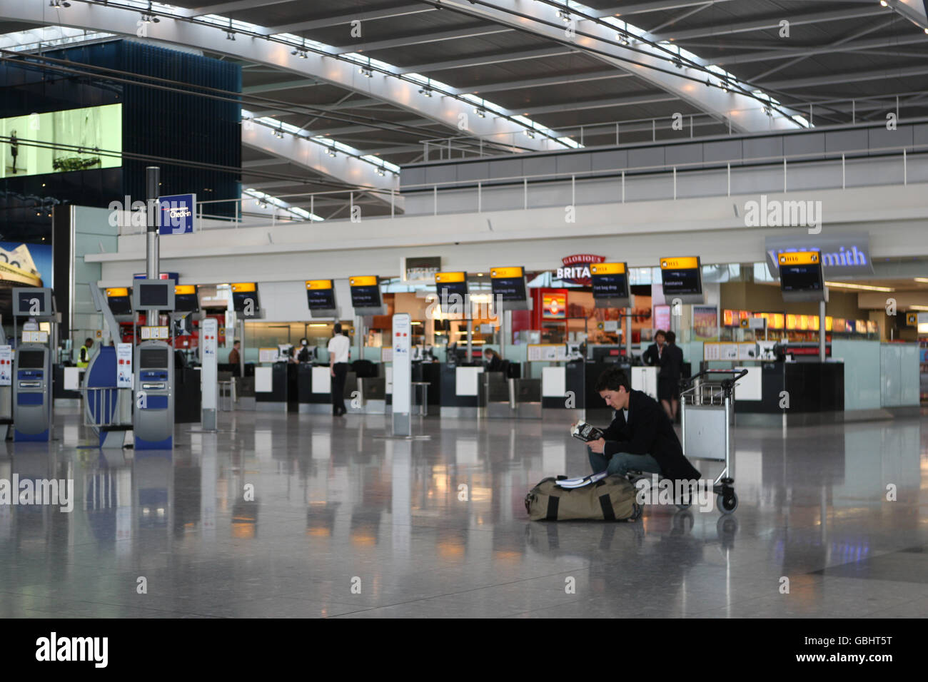 A passenger sits and waits on a trolley in departures of Terminal 5 at