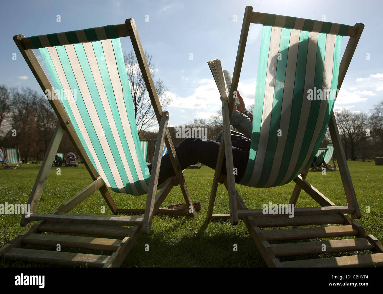 Karin Kolbe reads a book in the sun on deckchairs in Green Park, in