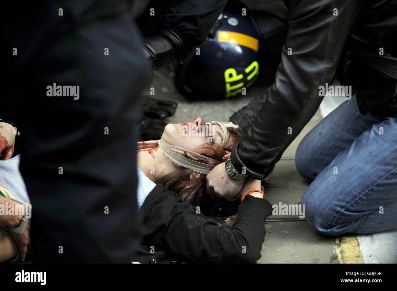 A woman lays seriously injured and is attended by police and medics near Queen Victoria Street in the centre of London during the G20 protests. Stock Photo