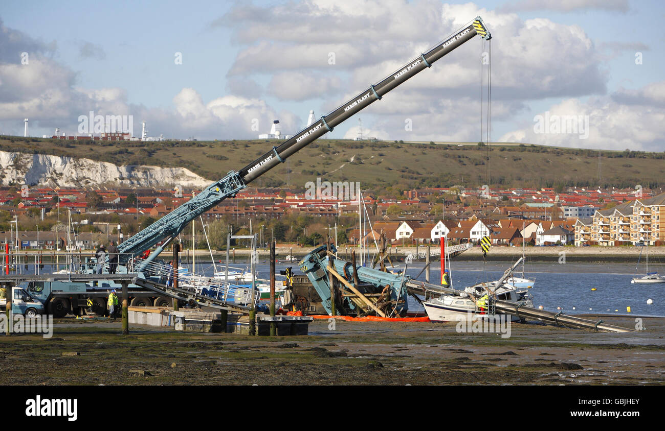 Salvage workers attempt to recover a crane which toppled over crushing a new 20,000 yacht at Portchester near Portsmouth. Stock Photo