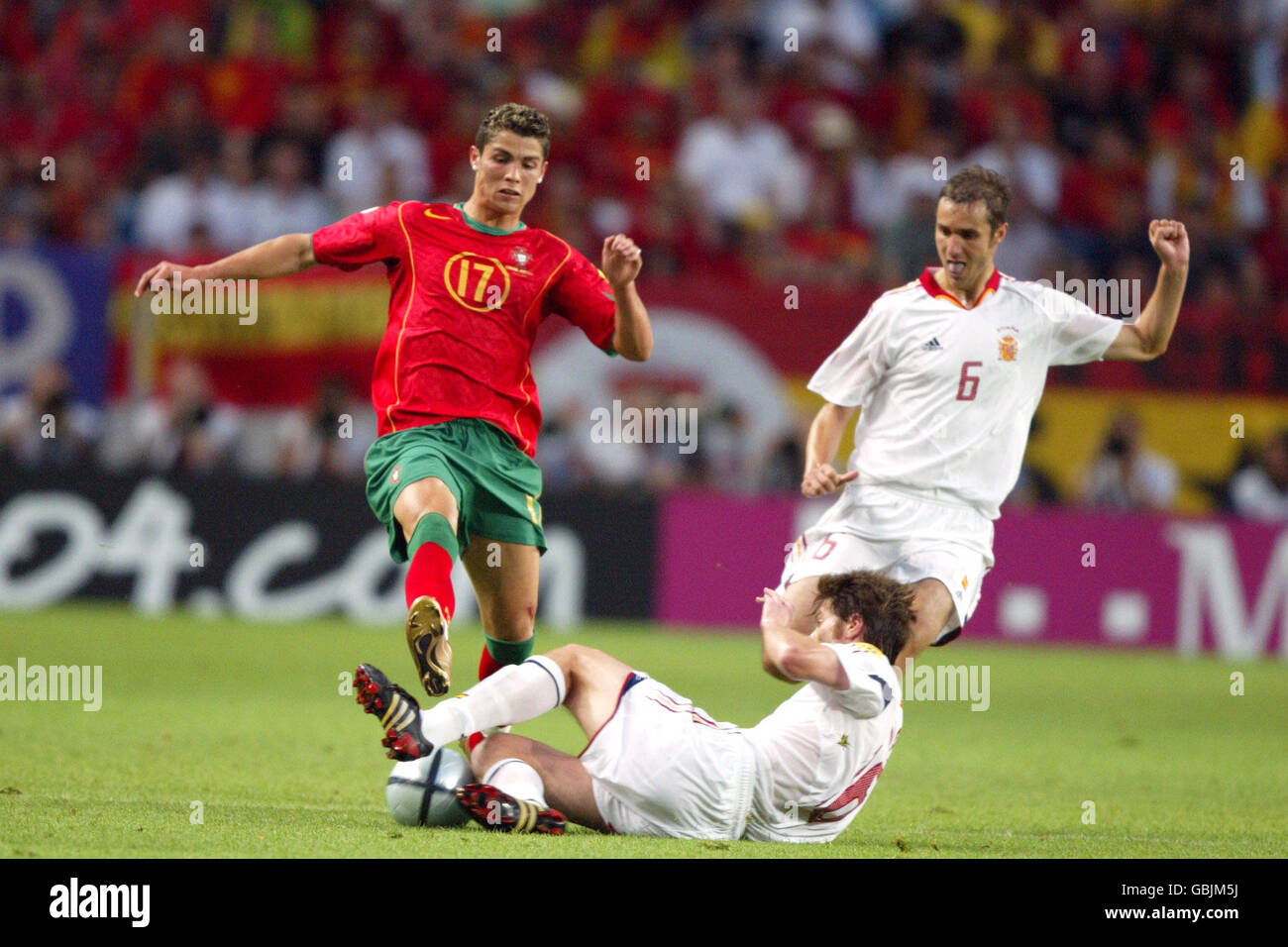 Spain's Xabi Alonso (c) slides in to tackle Portugal's Cristiano Ronaldo (l) as teammate Ivan Helguera (r) looks on Stock Photo