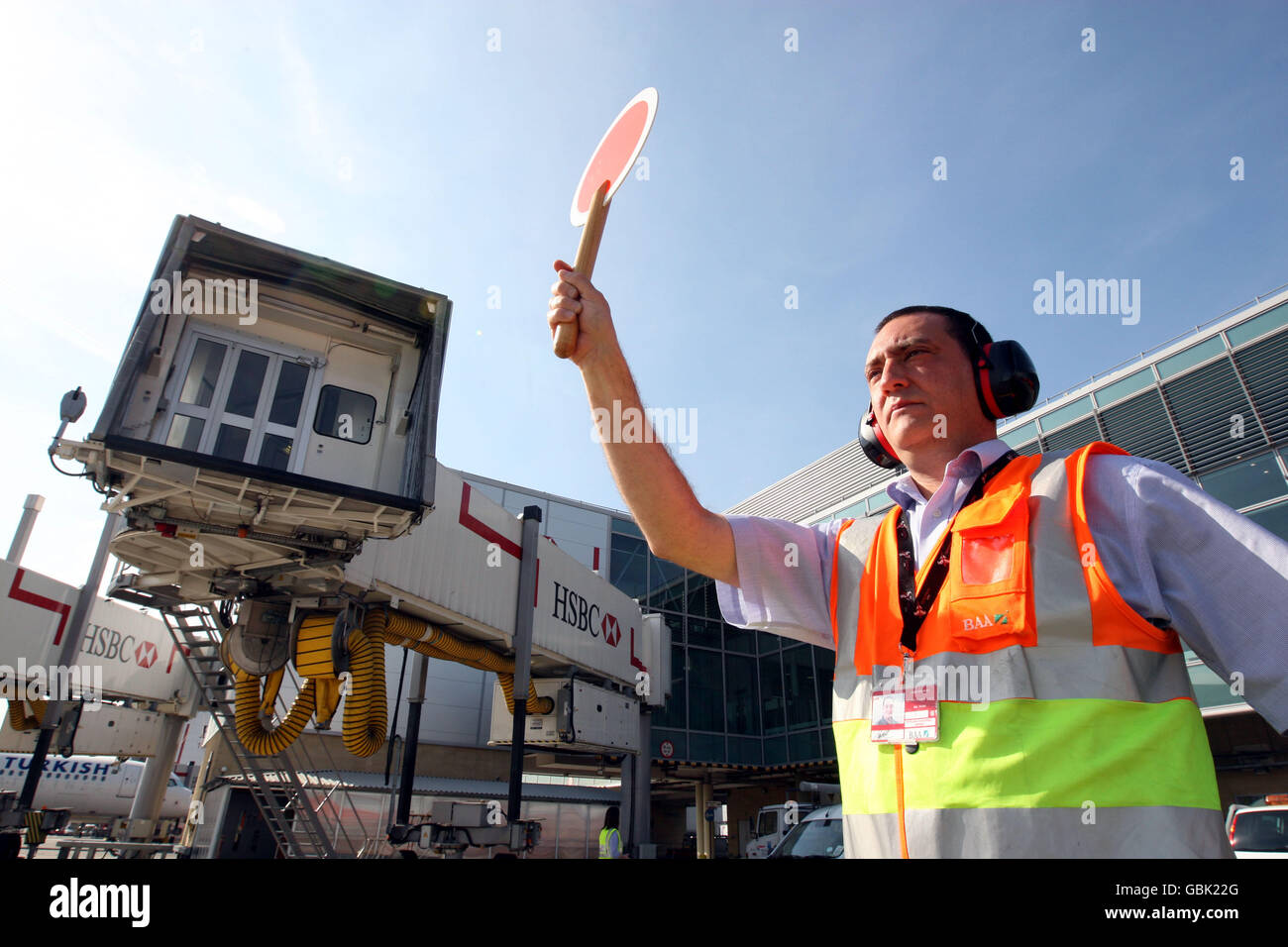 A plane is marshalled onto its stand by a marshaller from the Airside Operations Safety Unit at Heathrow Airport, Middlesex. Marshalling uses internationally recognised signals to position and stop arriving aircraft. Stock Photo