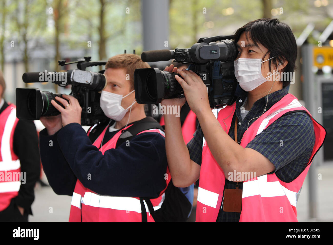 TV crews wear paper masks while filming arrivals at London Heathow
