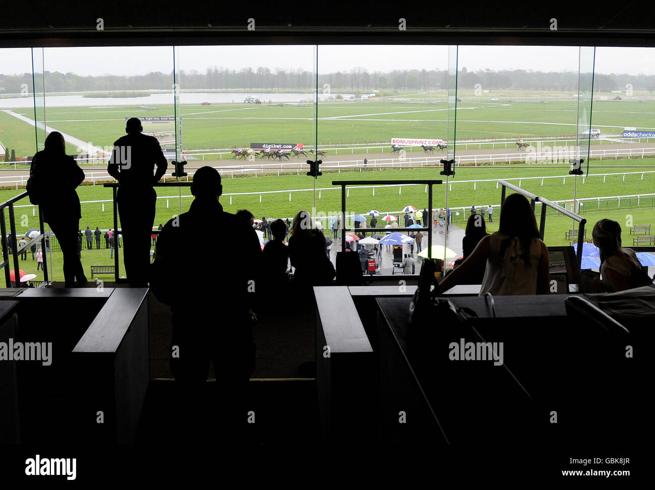 Racegoers watch from the glass fronted restaurant during the oddschecker.com Easter and Masaka Stakes Day at Kempton Park Racecourse. Stock Photo