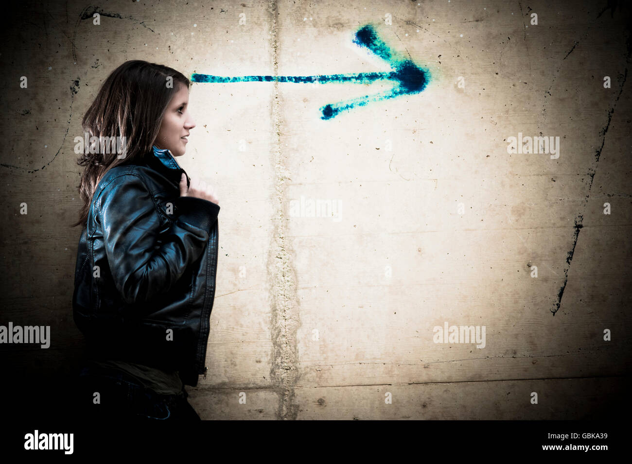 Young woman looking in the direction of an arrow Stock Photo