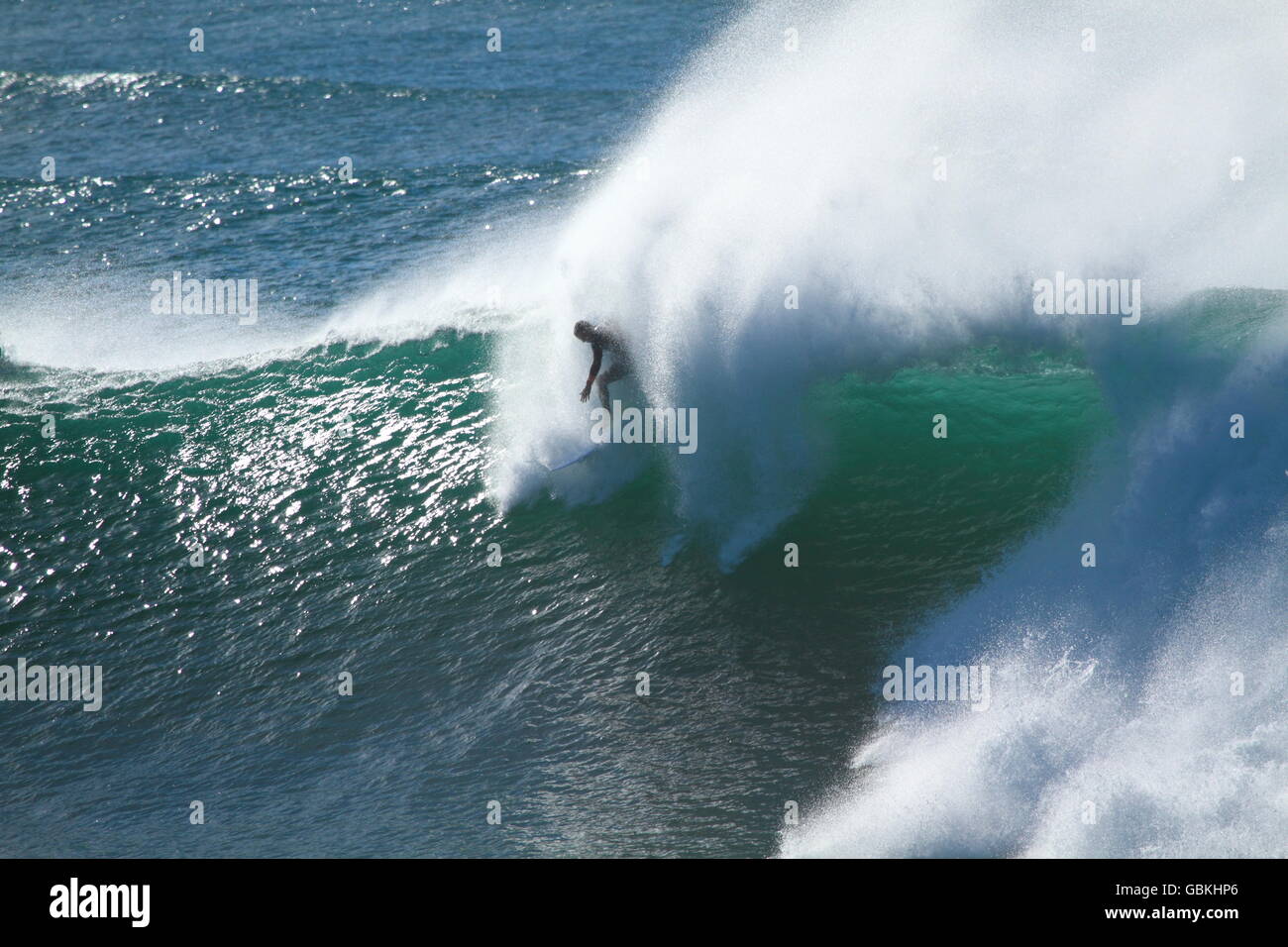 A lone male surfer drops in on a large wave during big surf at Sandon Point, Bulli, NSW, Australia. Stock Photo