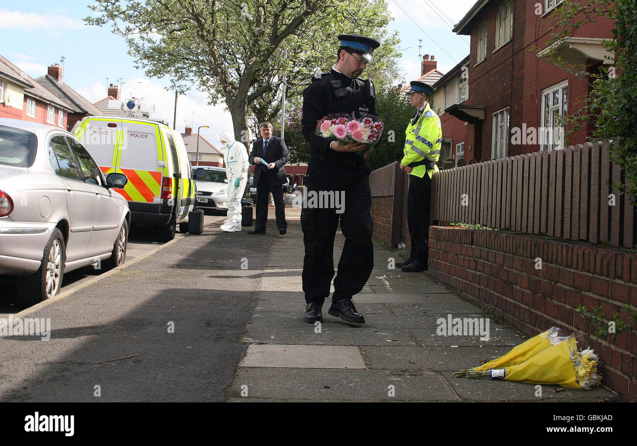 A police officer lays floral tributes outside a house on Oakdale Avenue in Wallasey, Merseyside where a four-year-old girl was found murdered. Stock Photo