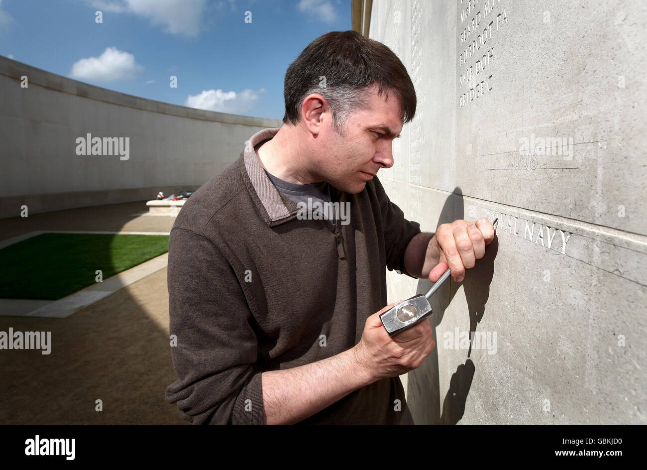 Stone mason Nick Hindle starts the process of carving another 67 names onto the 'Armed Forces Memorial' at the National Memorial Arboretum near Alrewas, Staffordshire. Stock Photo