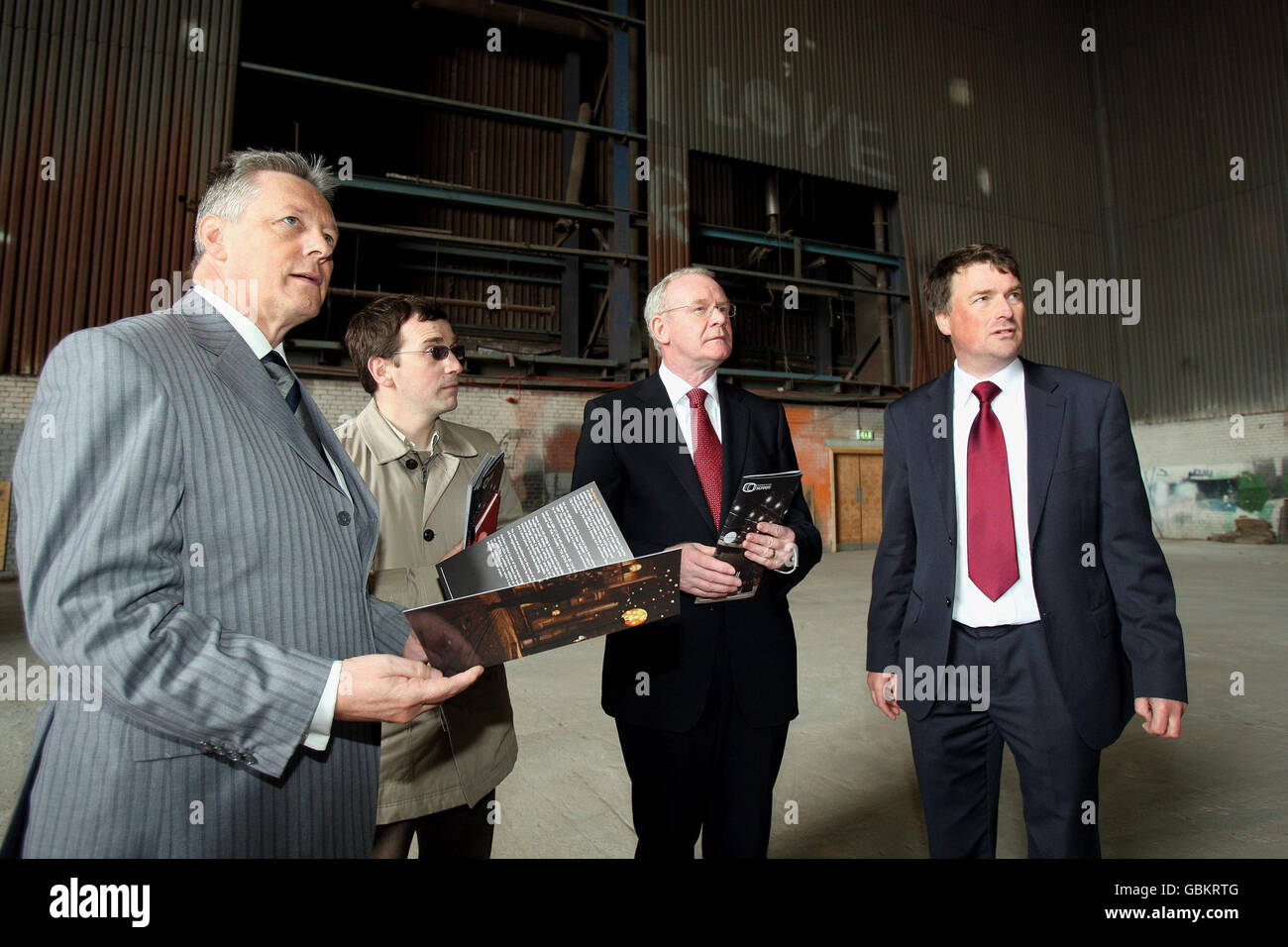 First Minister Peter Robinson (left) with Deputy First Minister Martin McGuinness (second right) with Andrew Reid (second left) and Rick Hill (right) from Northern Ireland Screen, tour the paint factory in the Titanic quarter of Belfast, which has been used as a film location. Stock Photo