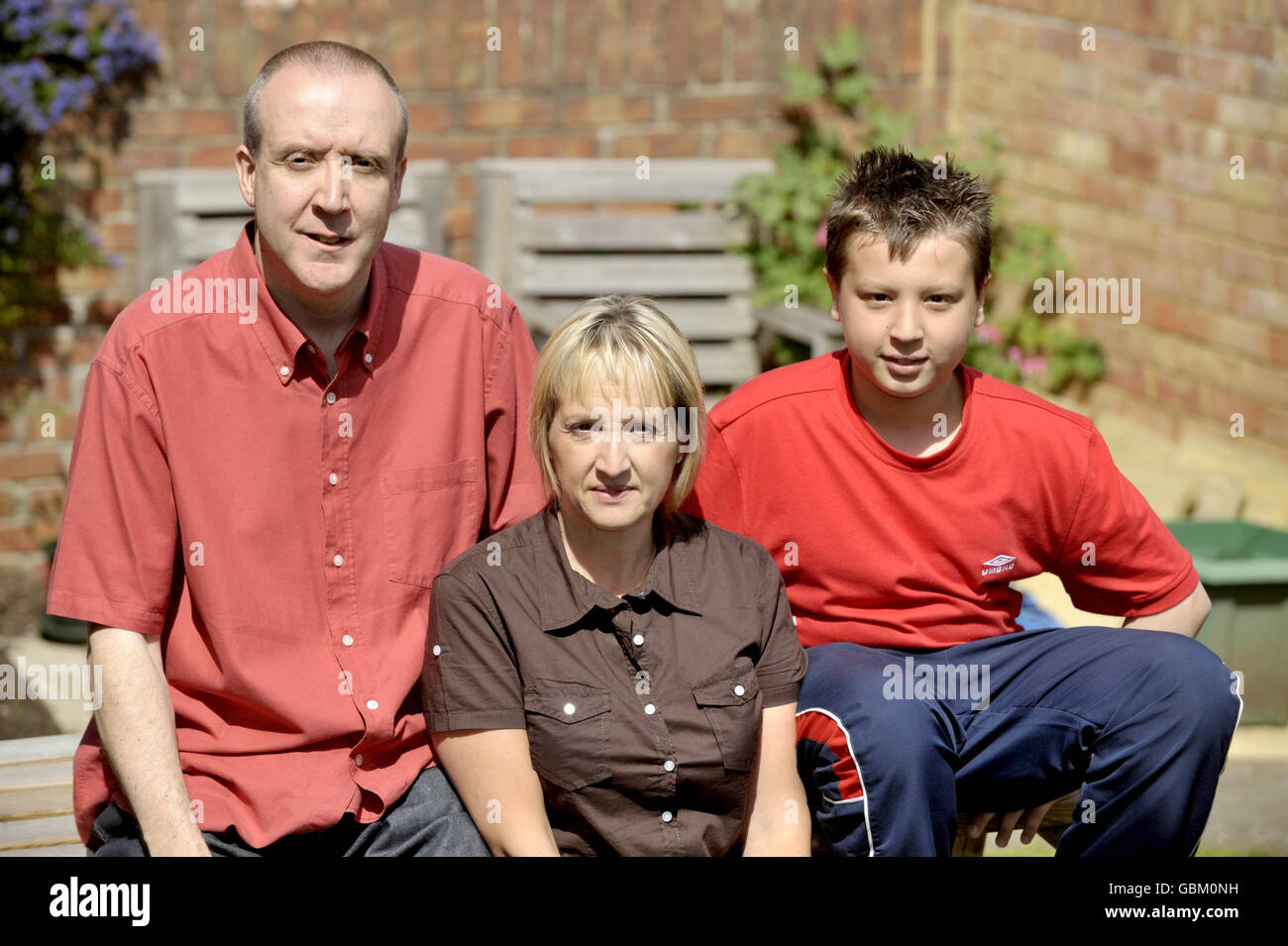 Barry Greatorex, 43, from Chipping Sodbury, in South Gloucestershire, stands at his garden gate with his wife Fran, 46, and son Jamie, 13, as he is stuck at home under quarantine with a confirmed case of swine flu. Stock Photo