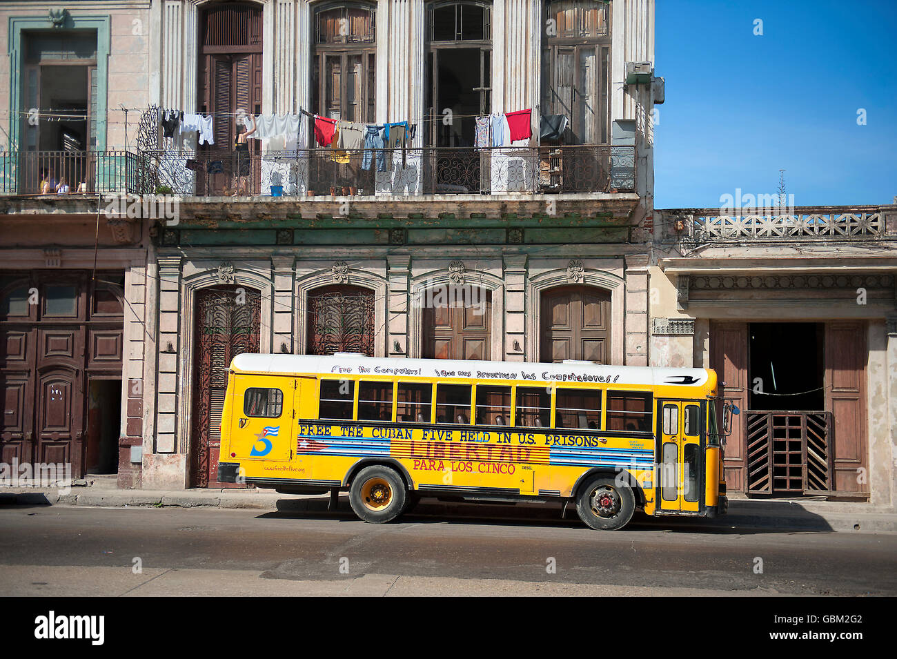 yellow school bus under clothesline with clothes hanging to dry Stock Photo