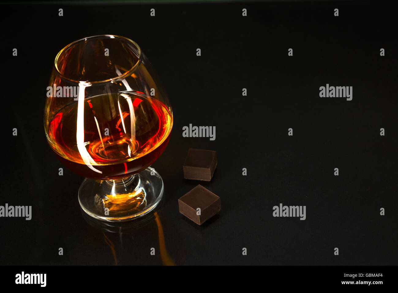 Brandy glass and chocolate on black background. Brandy glass. Cognac
