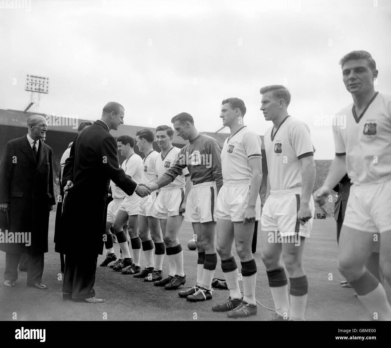 HRH The Duke of Edinburgh (l) shakes hands with Manchester United goalkeeper Ray Wood (fourth r) as United captain Roger Byrne (l, hidden) presents his team before the match. The other United players are (r-l) Duncan Edwards, Bobby Charlton, Bill Foulkes, Wood, Jackie Blanchflower, Liam Whelan, Tommy Taylor Stock Photo