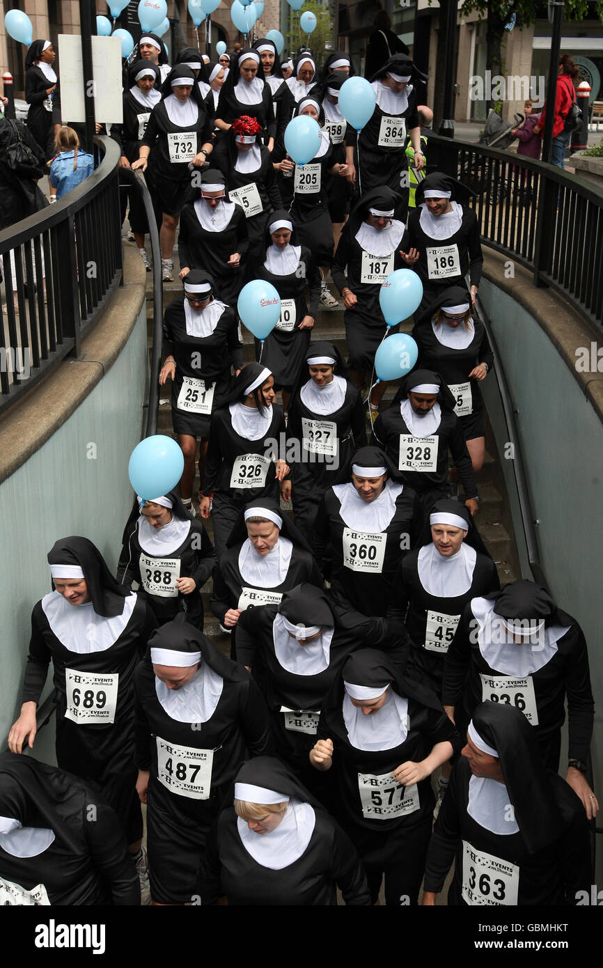 Hundreds of runners dressed as nuns enter a subway near Tower Bridge, London, as they take part in a charity 'Nun Run' to raise money for Barnardo's. Stock Photo
