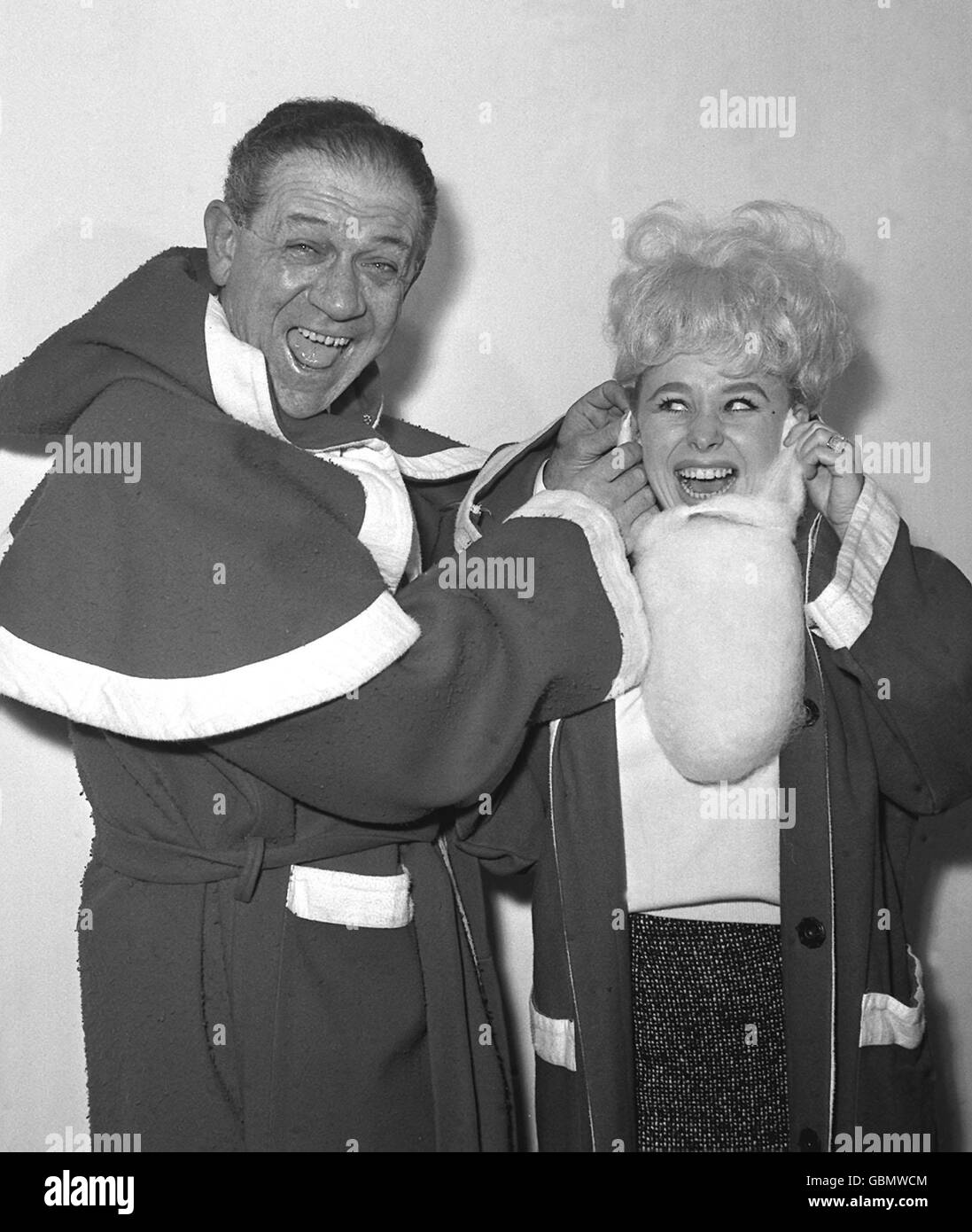 Sid James helps Barbara Windsor with her beard as the two dress up as Santa Claus for the Variety Club luncheon. Stock Photo