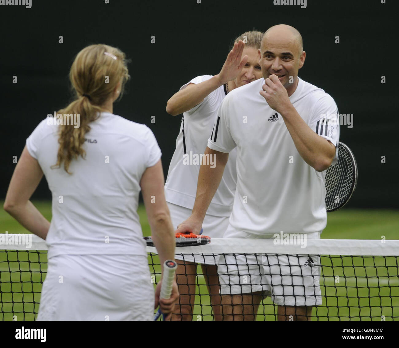 Former Wimbledon Champion Steffi Graf (behind) pretends to hit her husband and partner Andre Agassi after hitting Kim Clijsters (left) during the Centre Court Celebration at The All England Lawn Tennis and Croquet Club, Wimbledon, London. Stock Photo