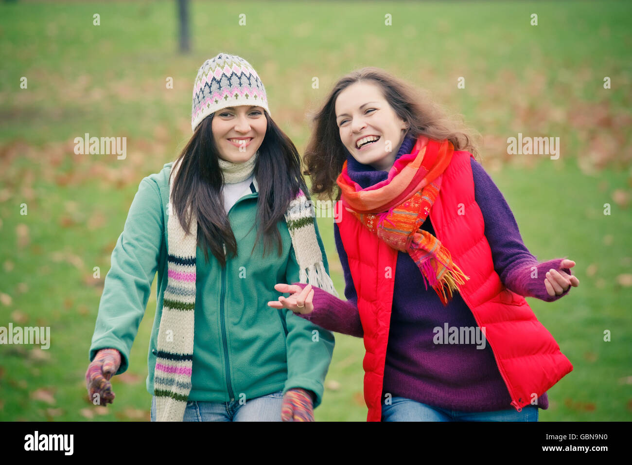 Two young woman walking in autumn park Stock Photo - Alamy