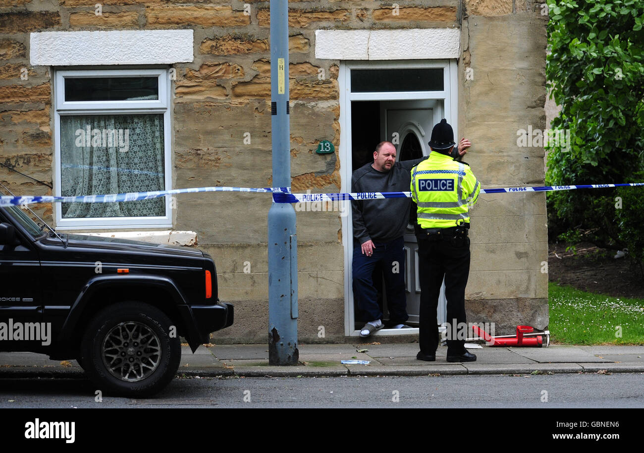 A neighbour talks to police at the scene in Shildon, County Durham where a man was shot last night. Stock Photo