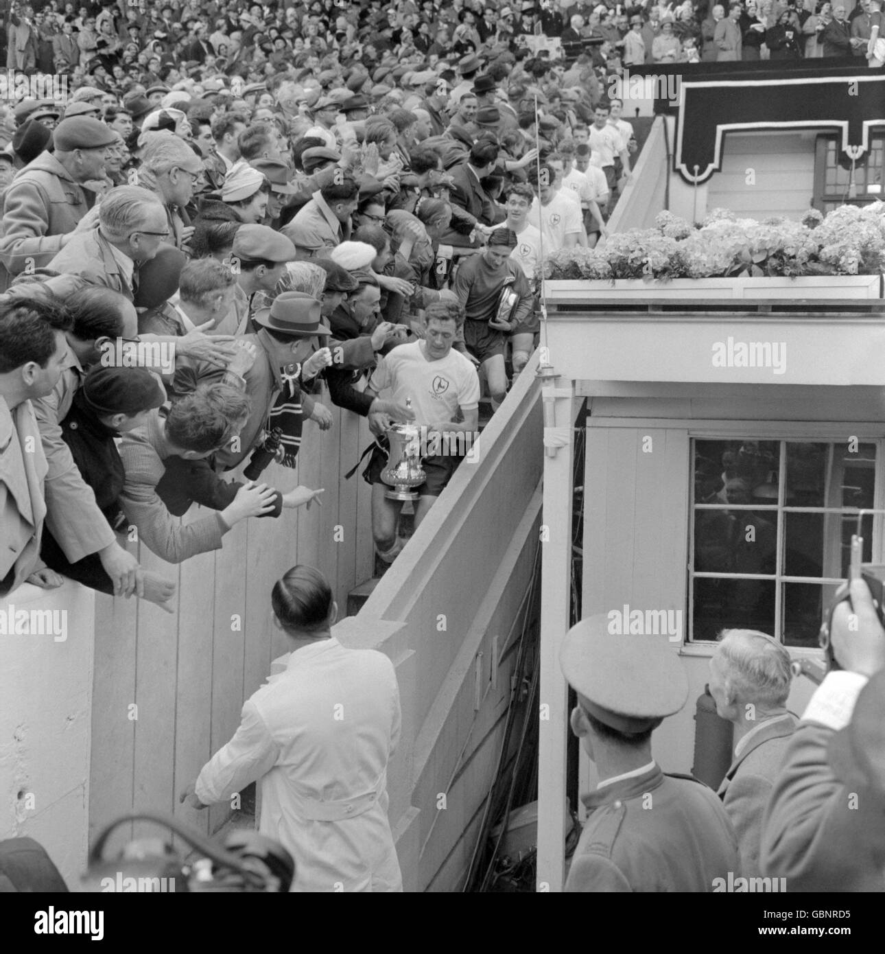 Tottenham Hotspur captain Danny Blanchflower clings onto the FA Cup as he is congratulated by enthusiastic fans while leading his team back down the steps from the royal box Stock Photo