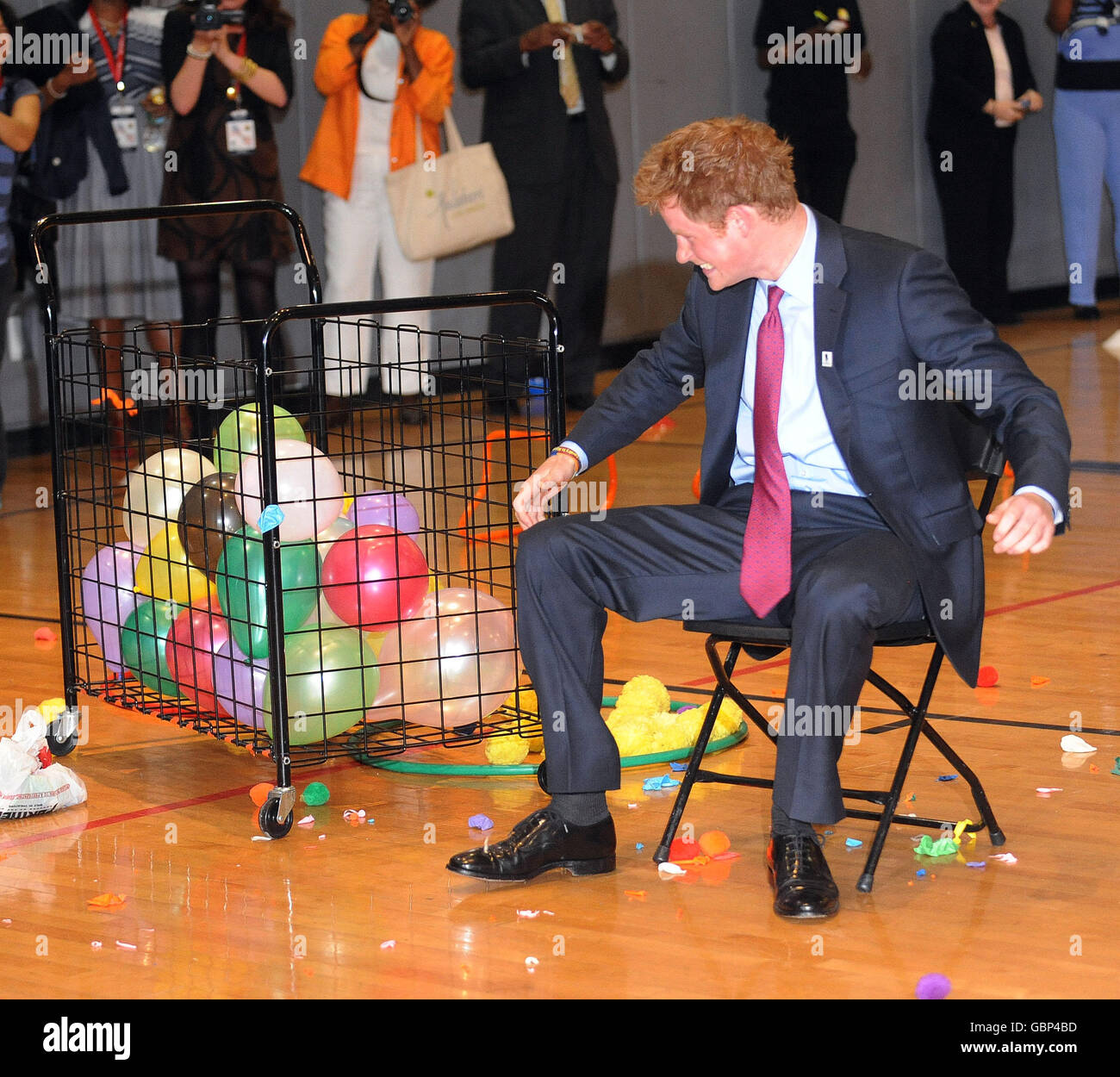 Pieces of balloon fly in all directions as Prince Harry takes part in a  race in the gym which included him sitting on a balloon to pop it during a  visit to