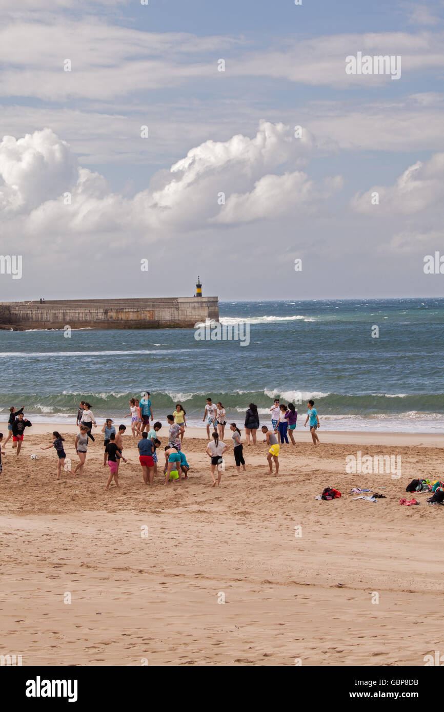 Teenagers playing ball games on the beach at Comillas Northern Spain Stock Photo