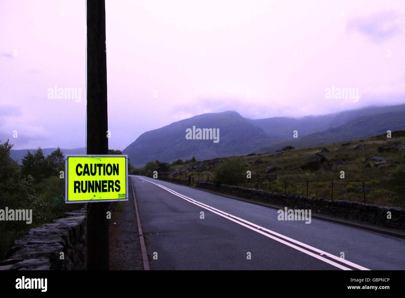 A sign on the main A5 road through Ogwen Valley warning drivers of runners crossing the road to their next climb as the RAF Mountain Rescue team search for runners who got caught up in treacherous weather during a fell race in the Snowdonia region in North Wales. Stock Photo