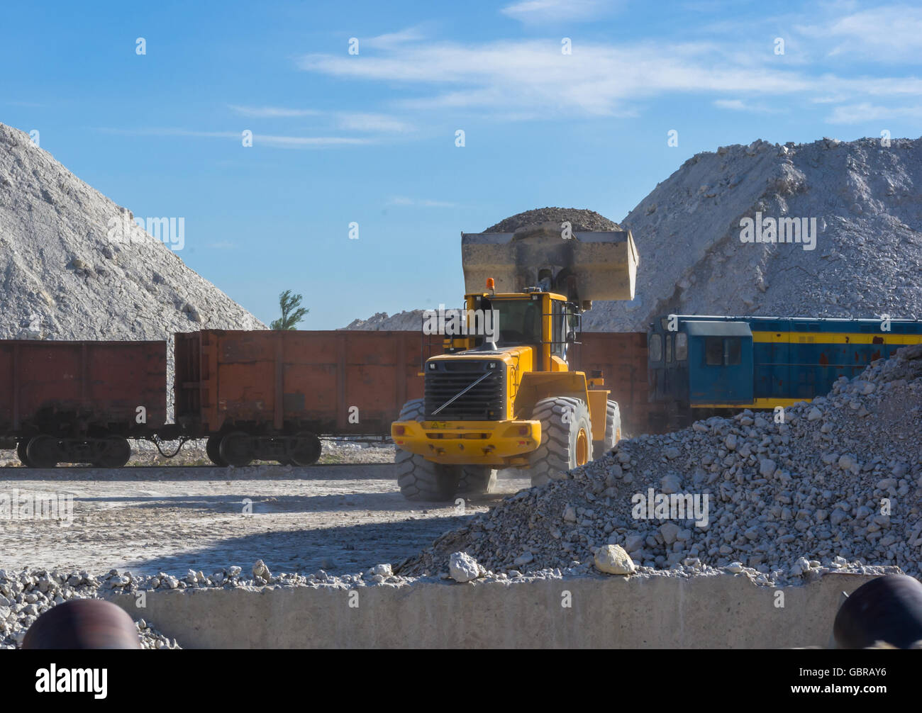 bucket loader loads the unique blue clay in railway cars Stock Photo