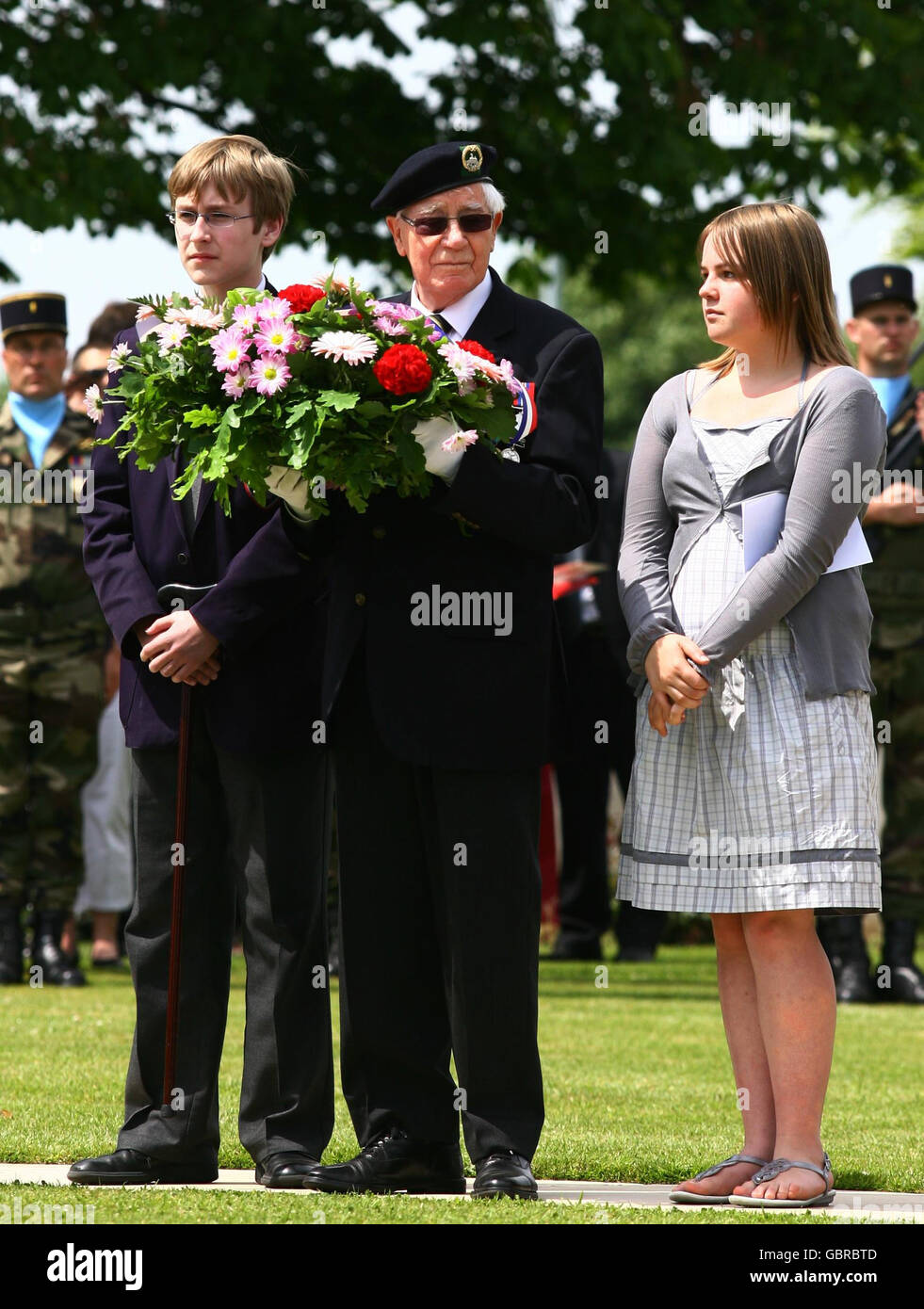 A Second World War veteran (centre) prepares to lay a wreath accompanied by family members at an international wreath laying ceremony at the Bayeux Military Cemetery in Normandy, France, ahead of tomorrows 65th anniversary of the D-Day landings. Stock Photo