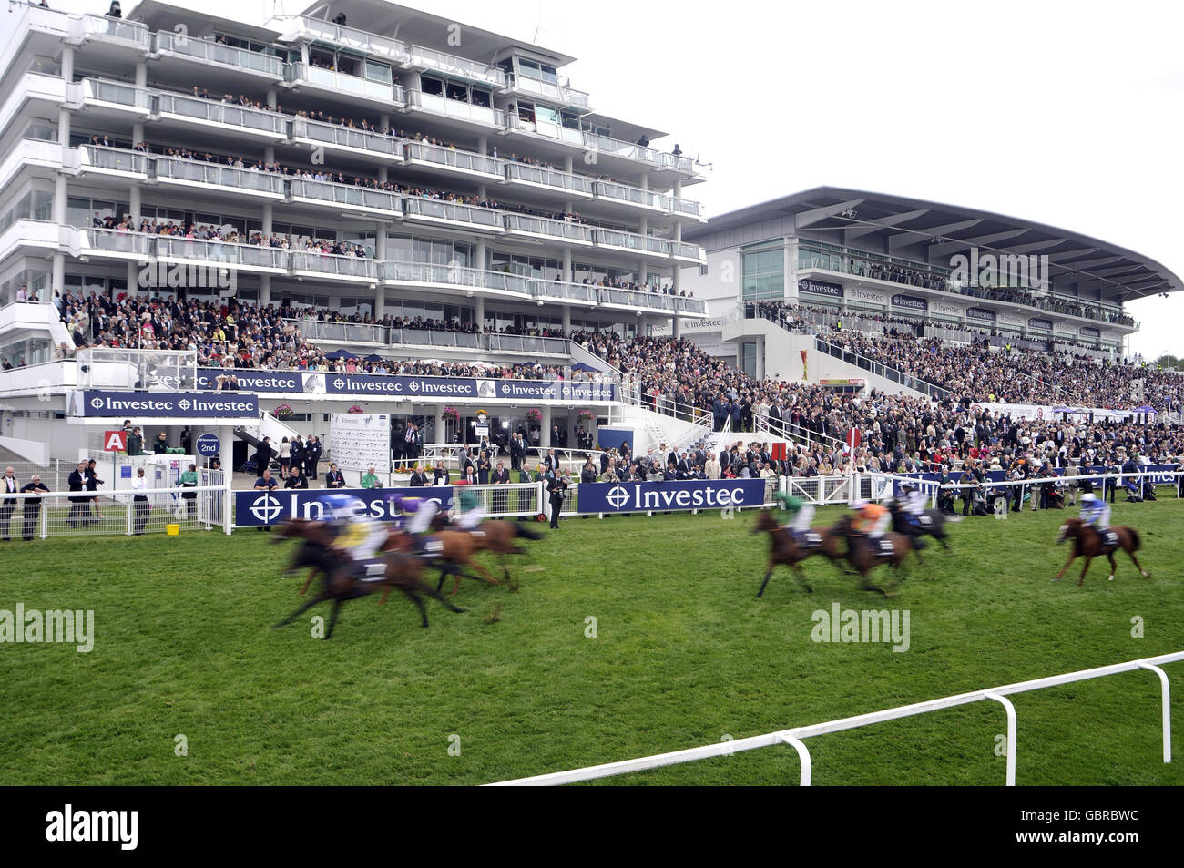 Runners race past the grandstand in The Investec Challenge during The Investec Ladies Day at Epsom Racecourse, London. Stock Photo