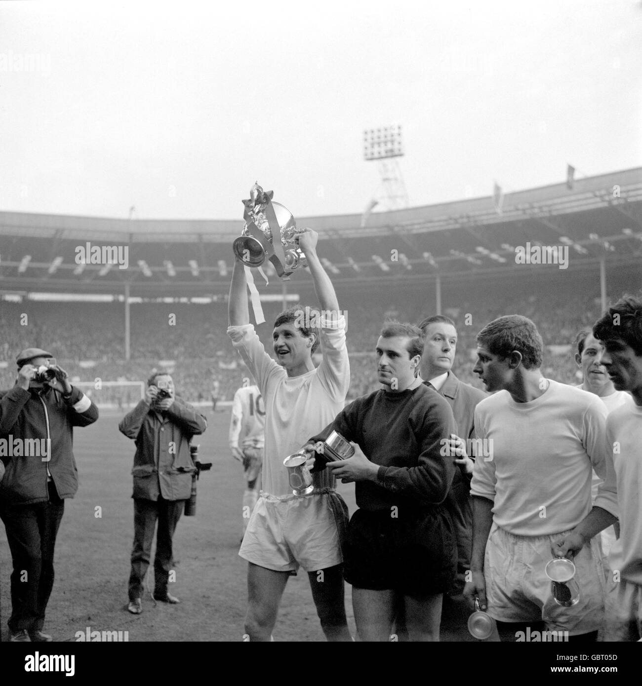 Queens Park Rangers captain Mike Keen (l) holds the League Cup aloft after his team's 3-2 win as goalkeeper Peter Springett (second l) holds onto the trophy's base Stock Photo