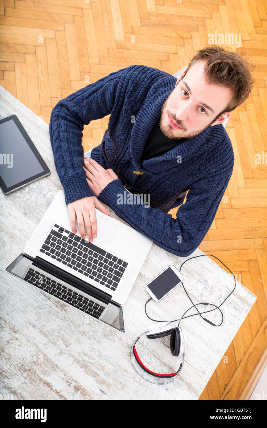 A young man working online from home with his laptop computer and