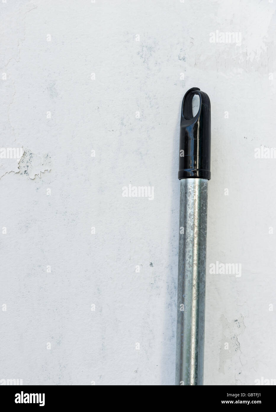 Dirty metal handle of the old swab near the house wall. Stock Photo