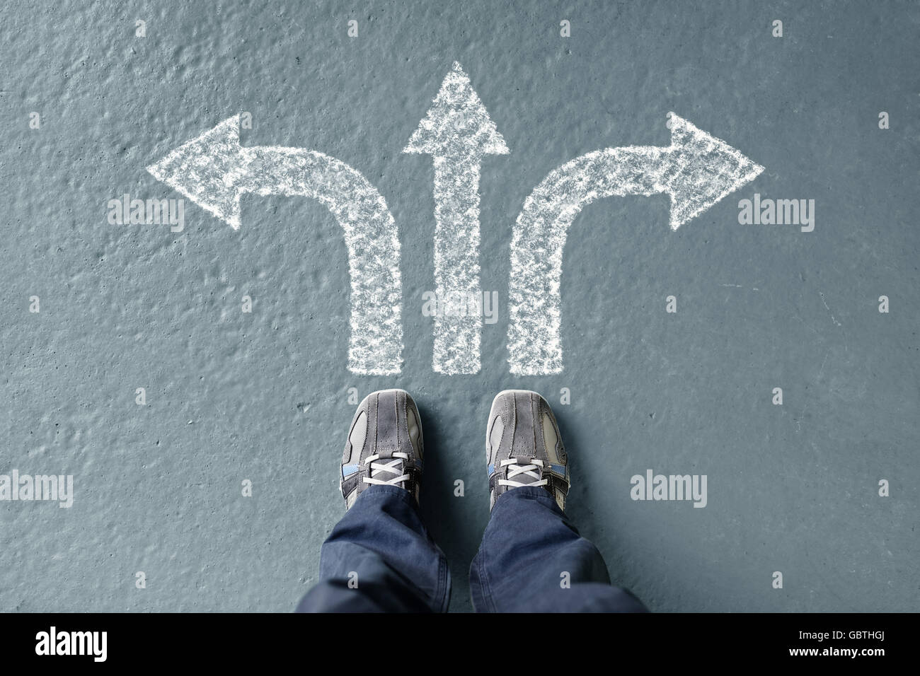 Taking decisions for the future man standing with three direction arrow choices, left, right or move forward Stock Photo