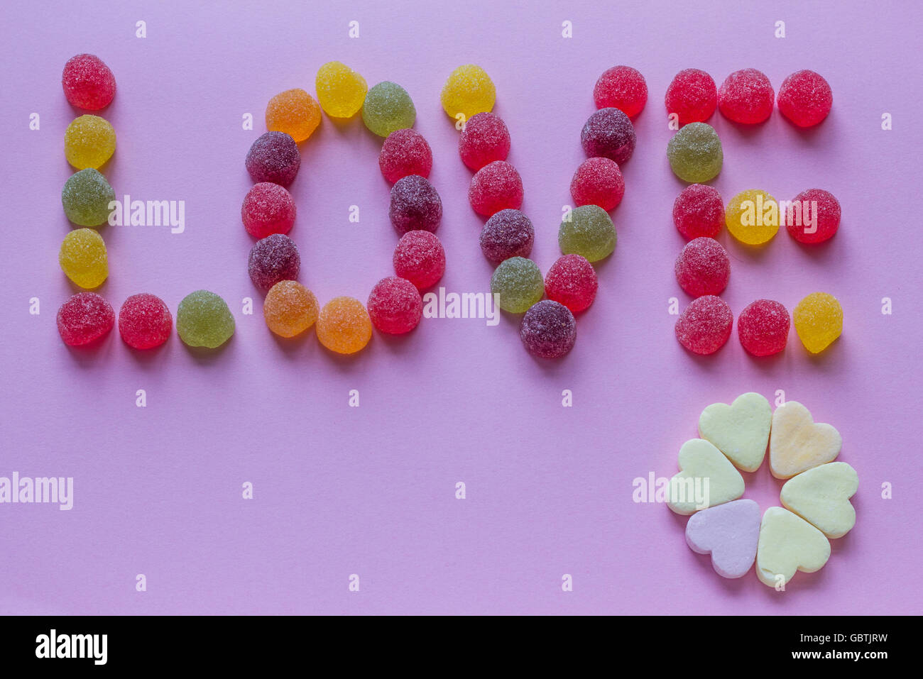 Word love spelled with candy on a purple background Stock Photo
