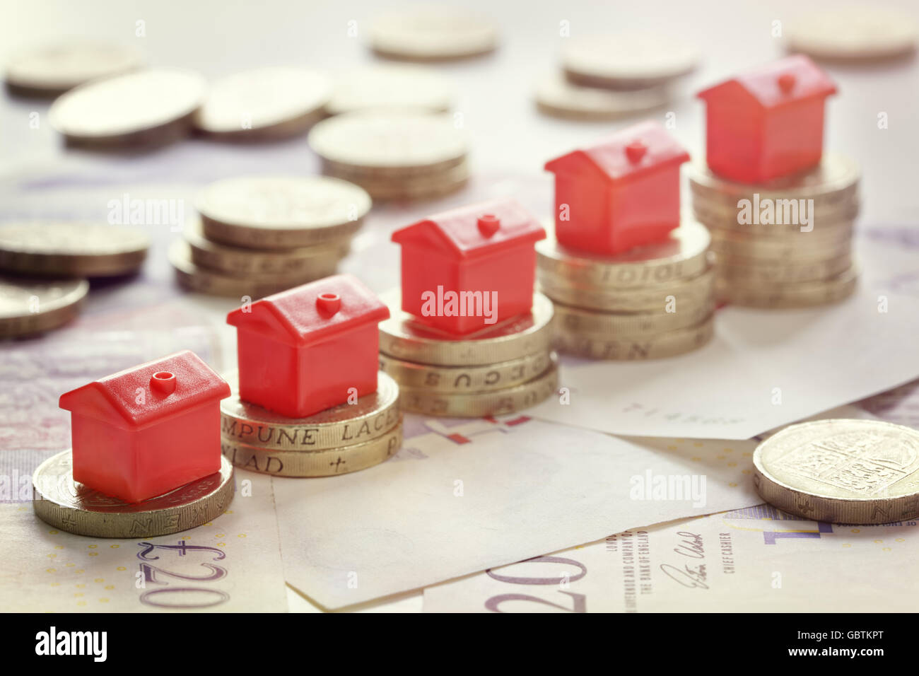 Minature houses resting on pound coin stacks concept for property ladder, mortgage and real estate investment Stock Photo