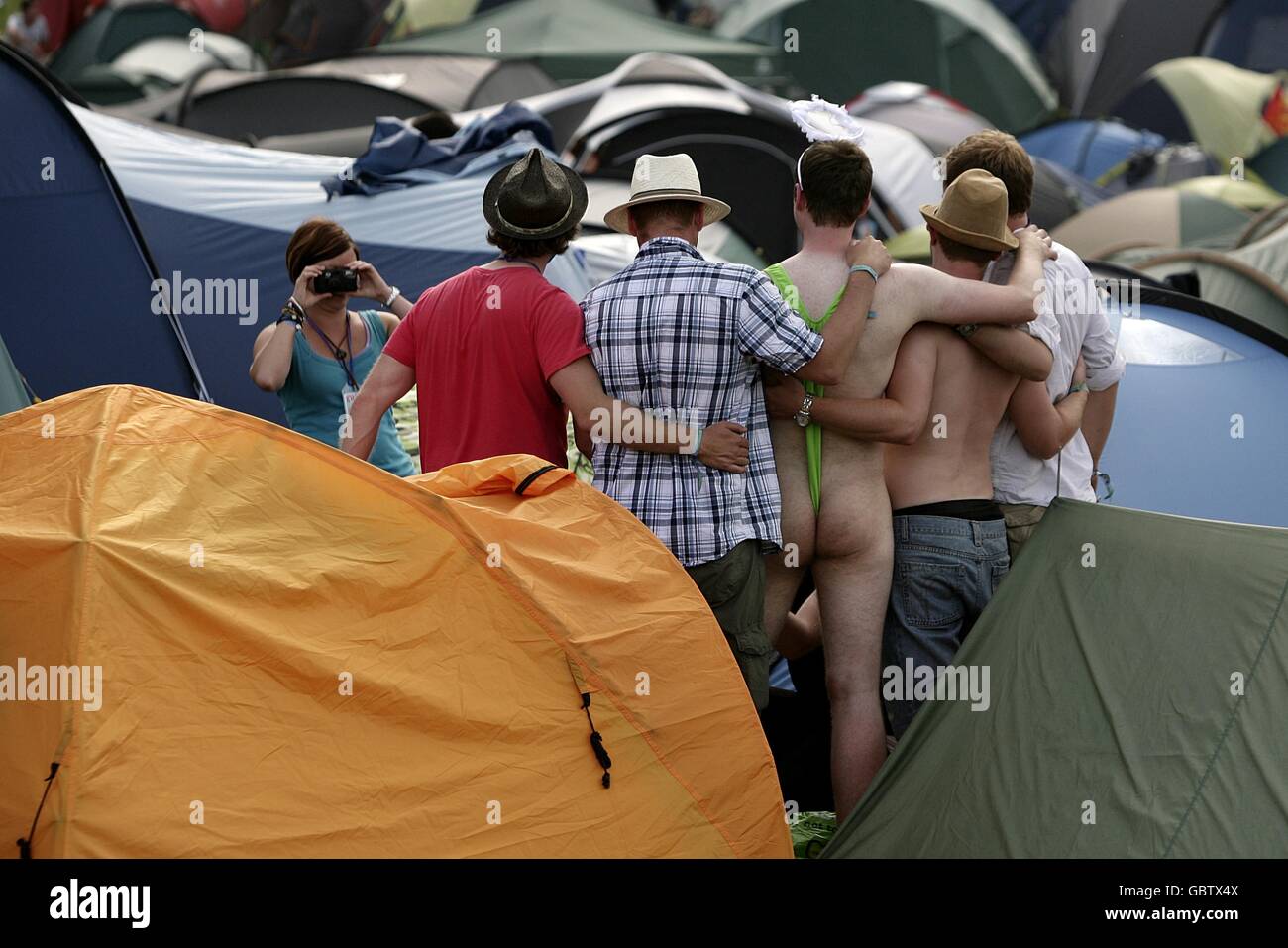 A festival goers pose for pictures with a man wearing a mankini during the 2009 Glastonbury Festival at Worthy Farm in Pilton, Somerset. Stock Photo