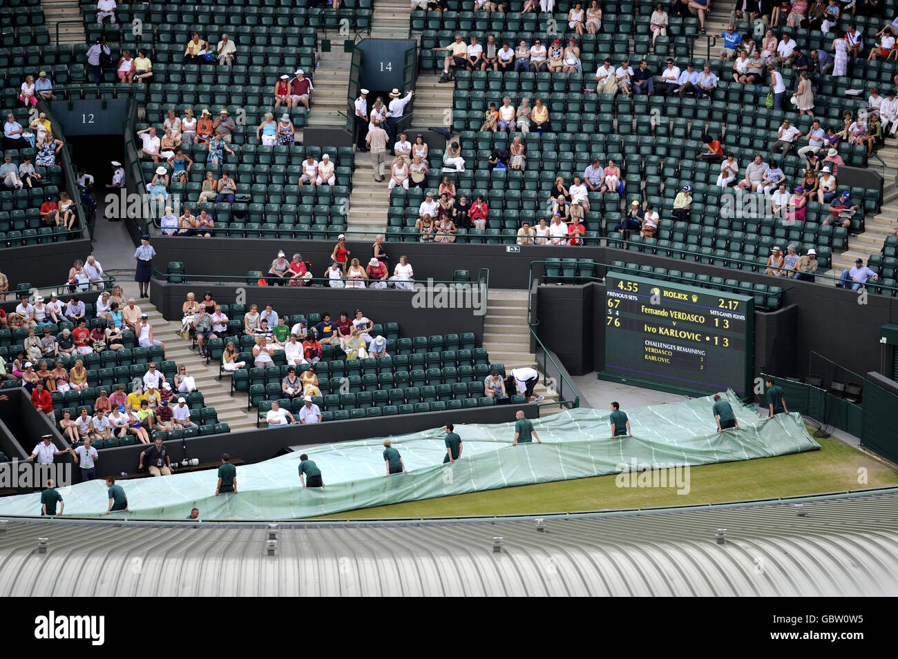 A view of the covers being taken off on Court One after rain delayed play during the Wimbledon Championships at the All England Lawn Tennis and Croquet Club, Wimbledon, London. Stock Photo